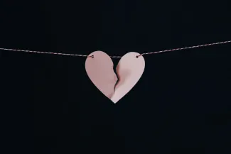 A paper heart on a sting. There is a large tear down the middle, but it hasn't split the heart in half yet.