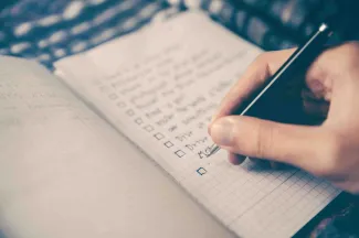 Person writing a list of financial goals in a notebook to plan for retirement and life priorities. 