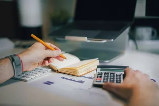 Individual reviewing tax documents and using a calculator to evaluate a 2025 IRA contribution before the tax deadline with a Greensboro, NC financial planner.
