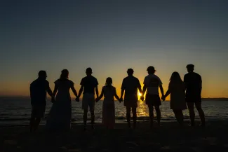 Family holding hands while walking on the beach at sunset representing retirement, legacy, and financial security