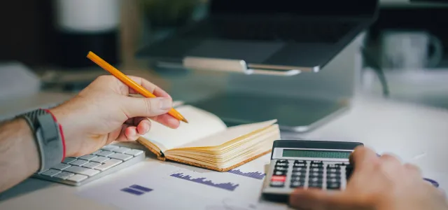 Individual reviewing tax documents and using a calculator to evaluate a 2025 IRA contribution before the tax deadline with a Greensboro, NC financial planner.